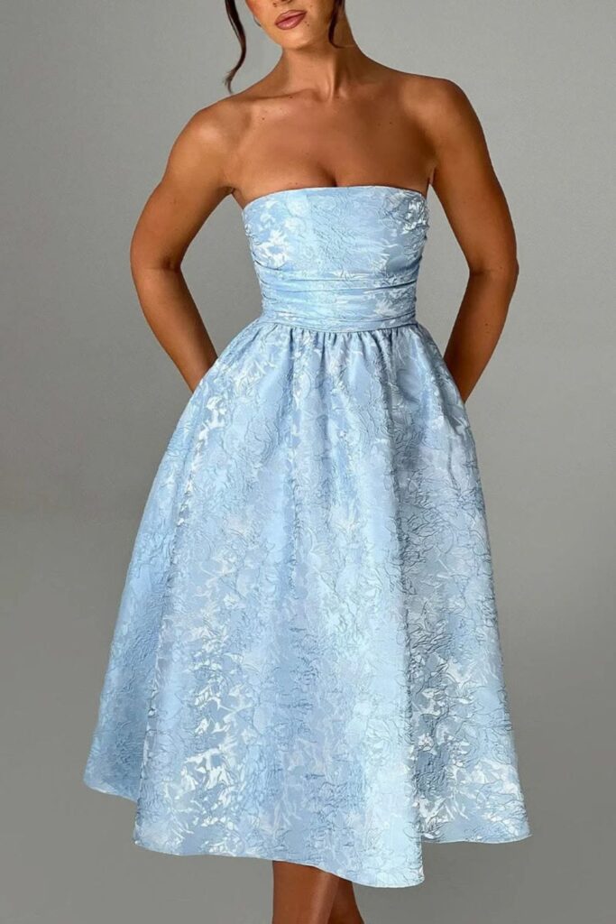 Woman wearing a strapless light blue jacquard midi dress with a textured floral pattern and cinched waist.